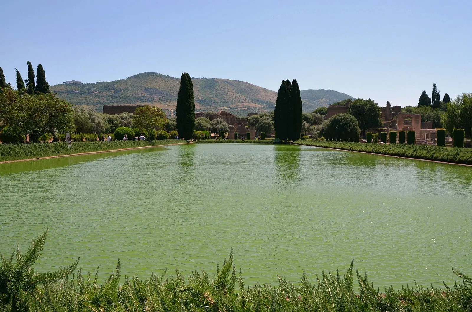 La grande vasca del Pecile a Villa Adriana circondata da cipressi e siepi, con i ruderi della villa e i monti Tiburtini sullo sfondo