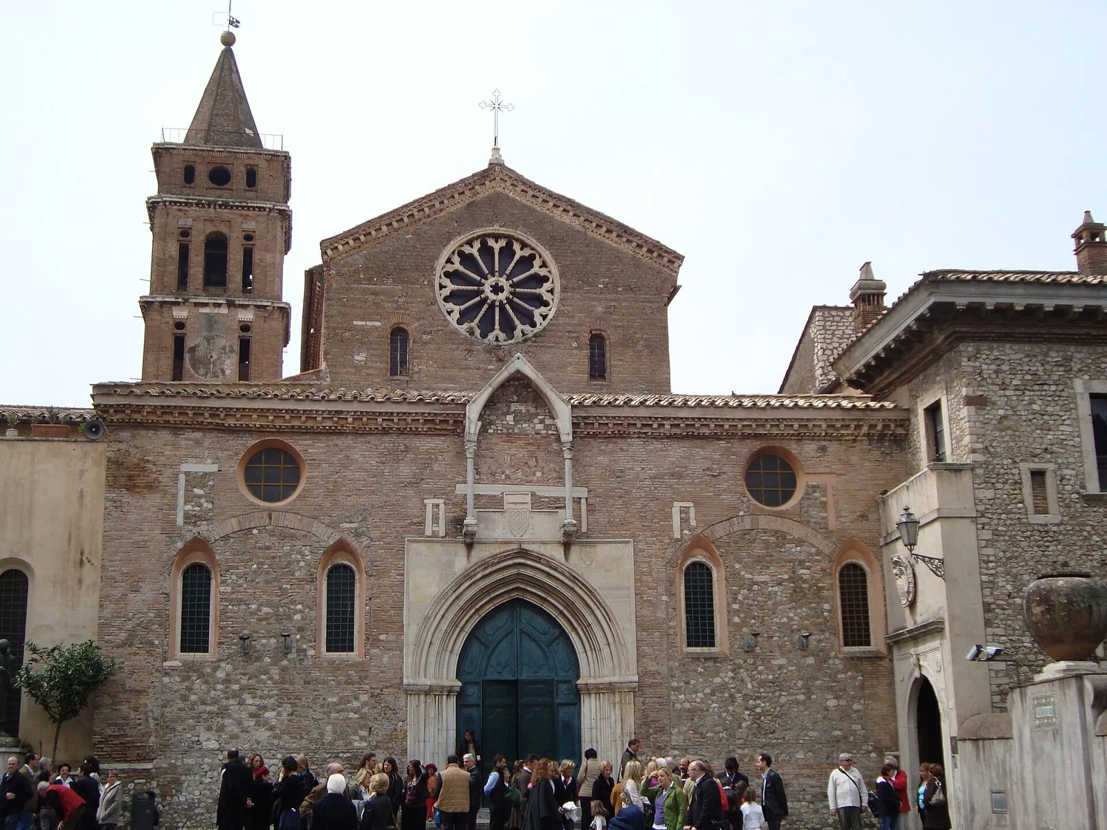 Facciata romanico-gotica della chiesa di Santa Maria Maggiore a Tivoli con rosone, portale ogivale e campanile, con persone sul sagrato
